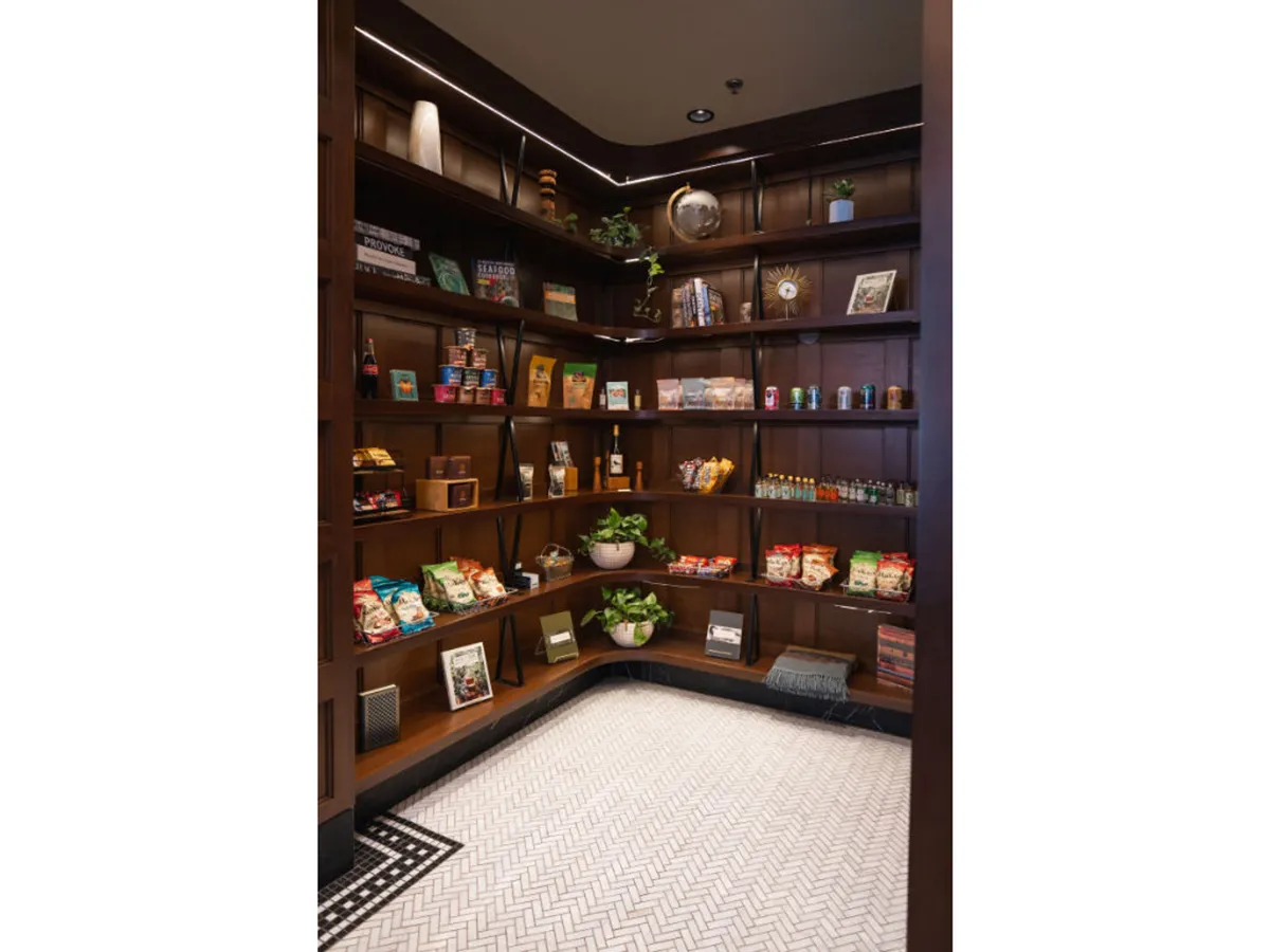 A well-stocked shelf area filled with snacks, local treats, and attractive green plants. The arrangement is both practical and aesthetically pleasing, suggesting easy access to amenities for guests on the go.