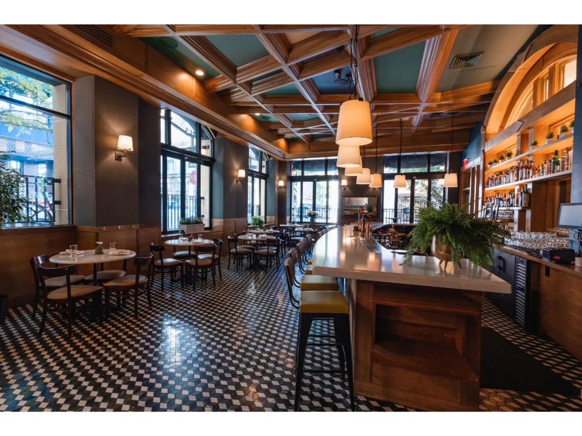 A relaxed and sociable bar area inside the hotel, with stylish lighting, dining tables, and a vibrant atmosphere. Guests are shown tasting unique cocktails and sharing meals, providing a sense of unwinding after urban exploration.