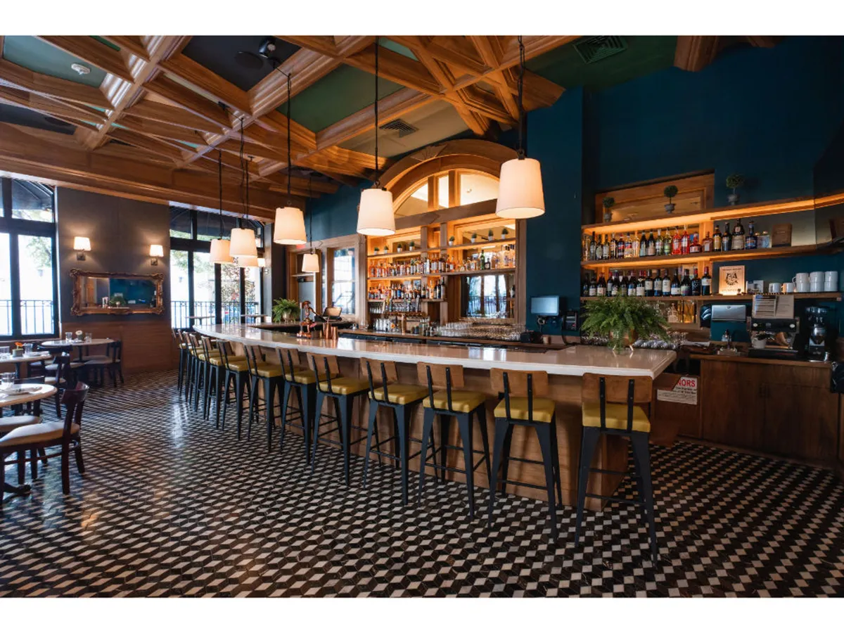 A lively bar area featuring a well-lit counter, contemporary lighting fixtures, an array of bottles, and stylish floor tiles. The scene is vibrant and sociable, perfect for enjoying signature drinks and connecting with others.